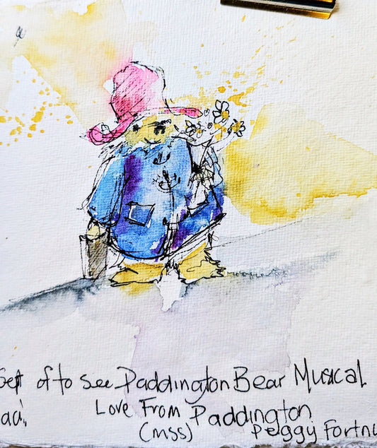 Watercolour sketch of Paddington Bear in blue duffle coat and red hat, painted by Sheila Gill
